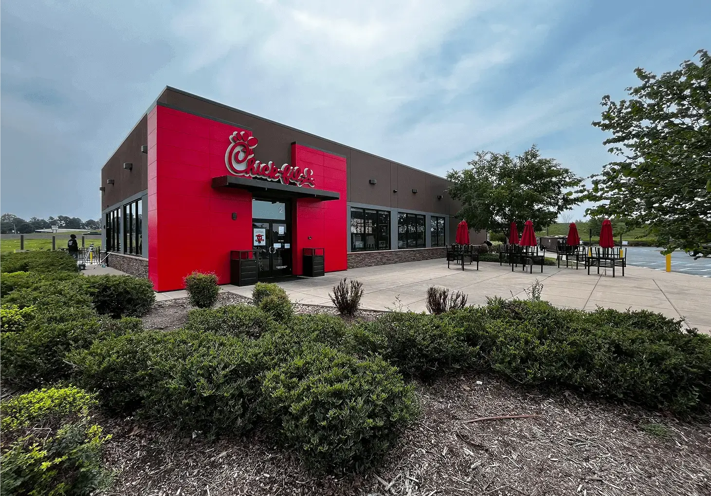 Exterior view of a Chick-fil-A restaurant with a red facade and outdoor seating.