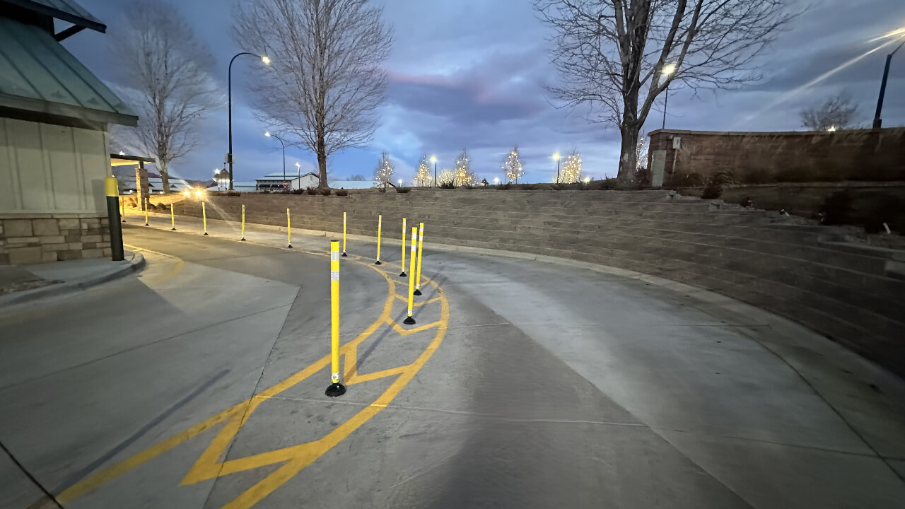 Drive-thru lane with yellow barriers at dusk.