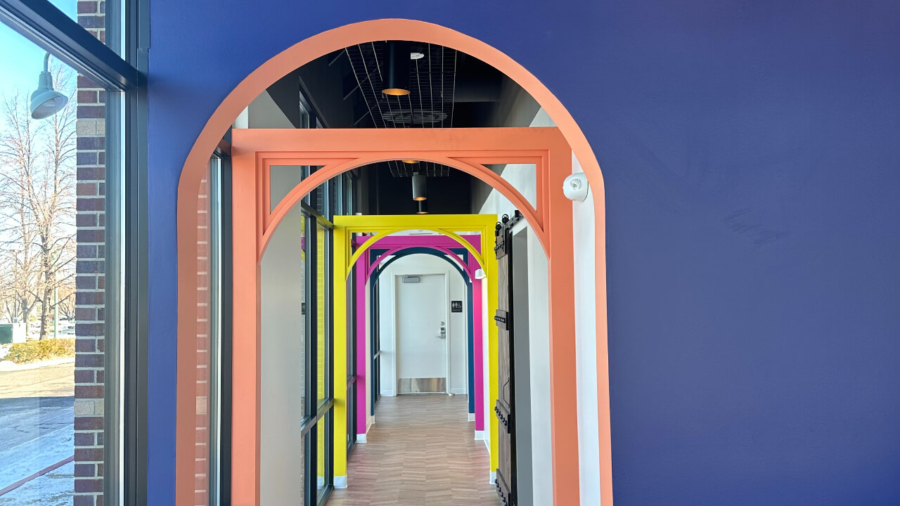 Colorful arched hallway with wooden floor.