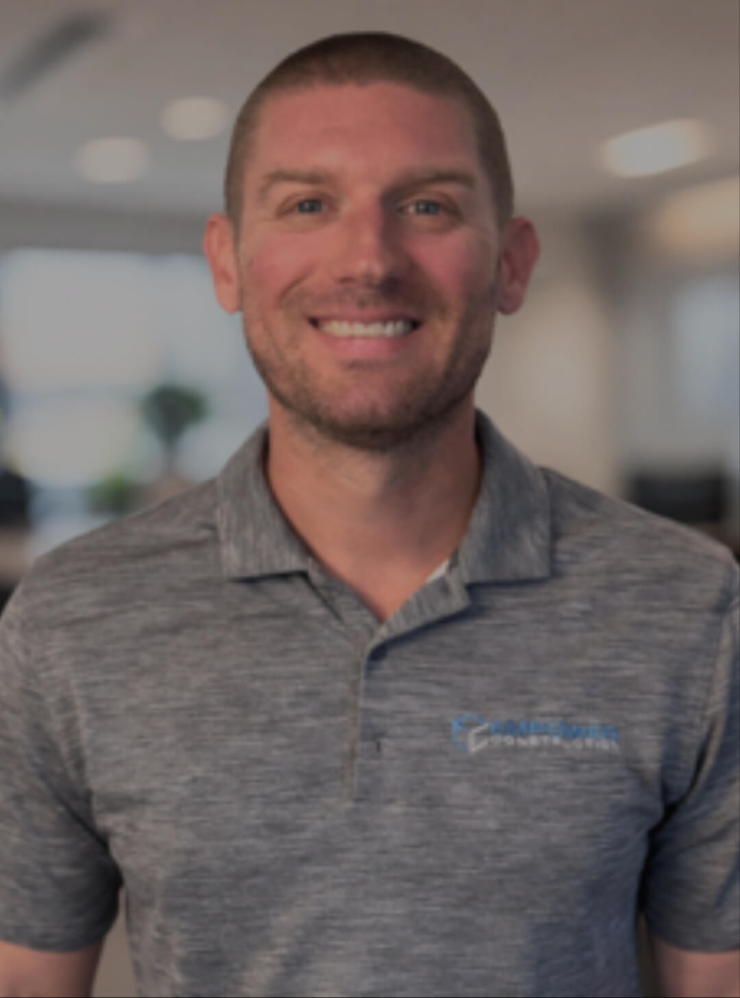 Smiling man in a gray polo shirt.