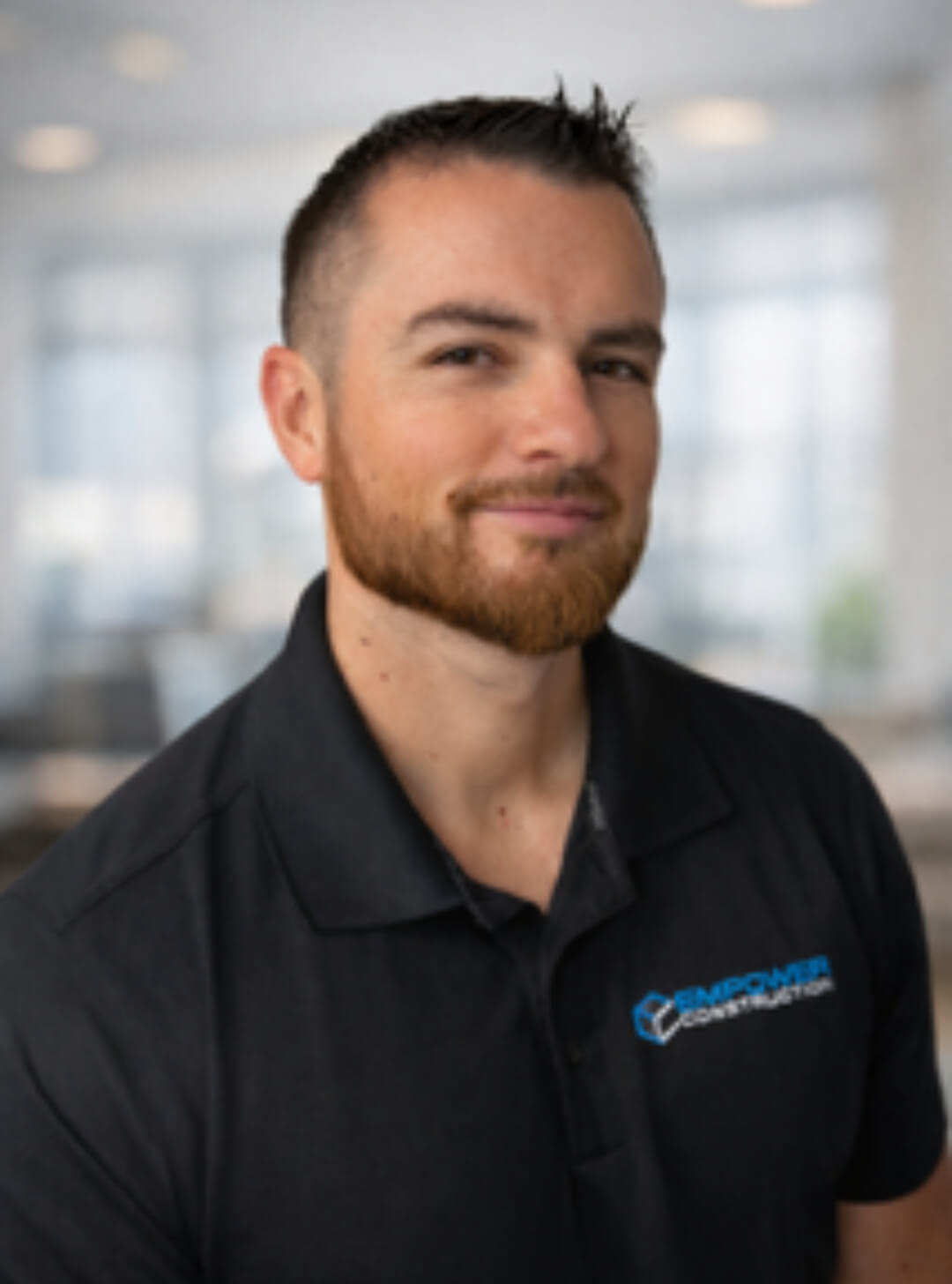 Man in black polo shirt, blurred background.