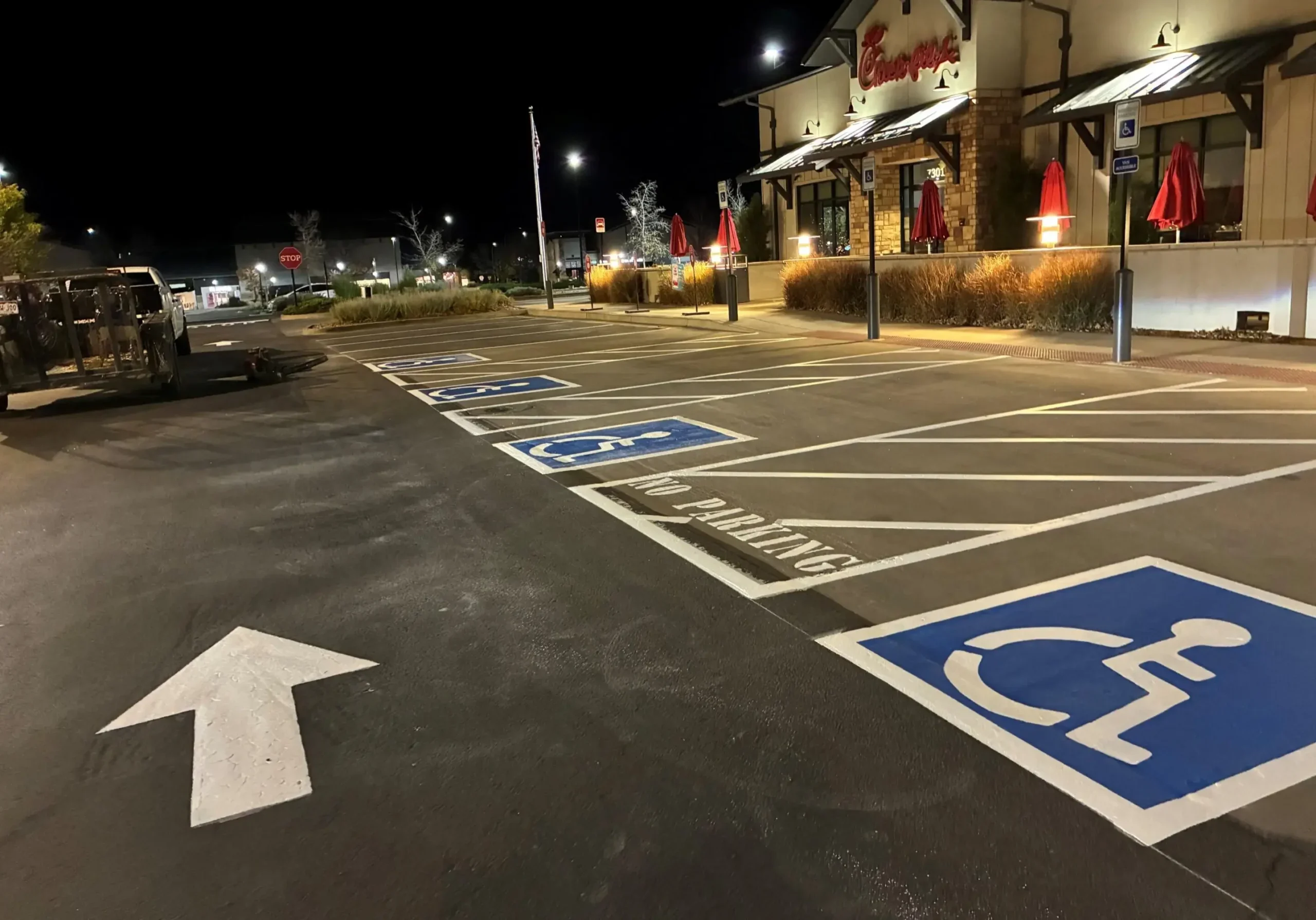 Empty handicapped parking spaces in a well-lit parking lot at night.